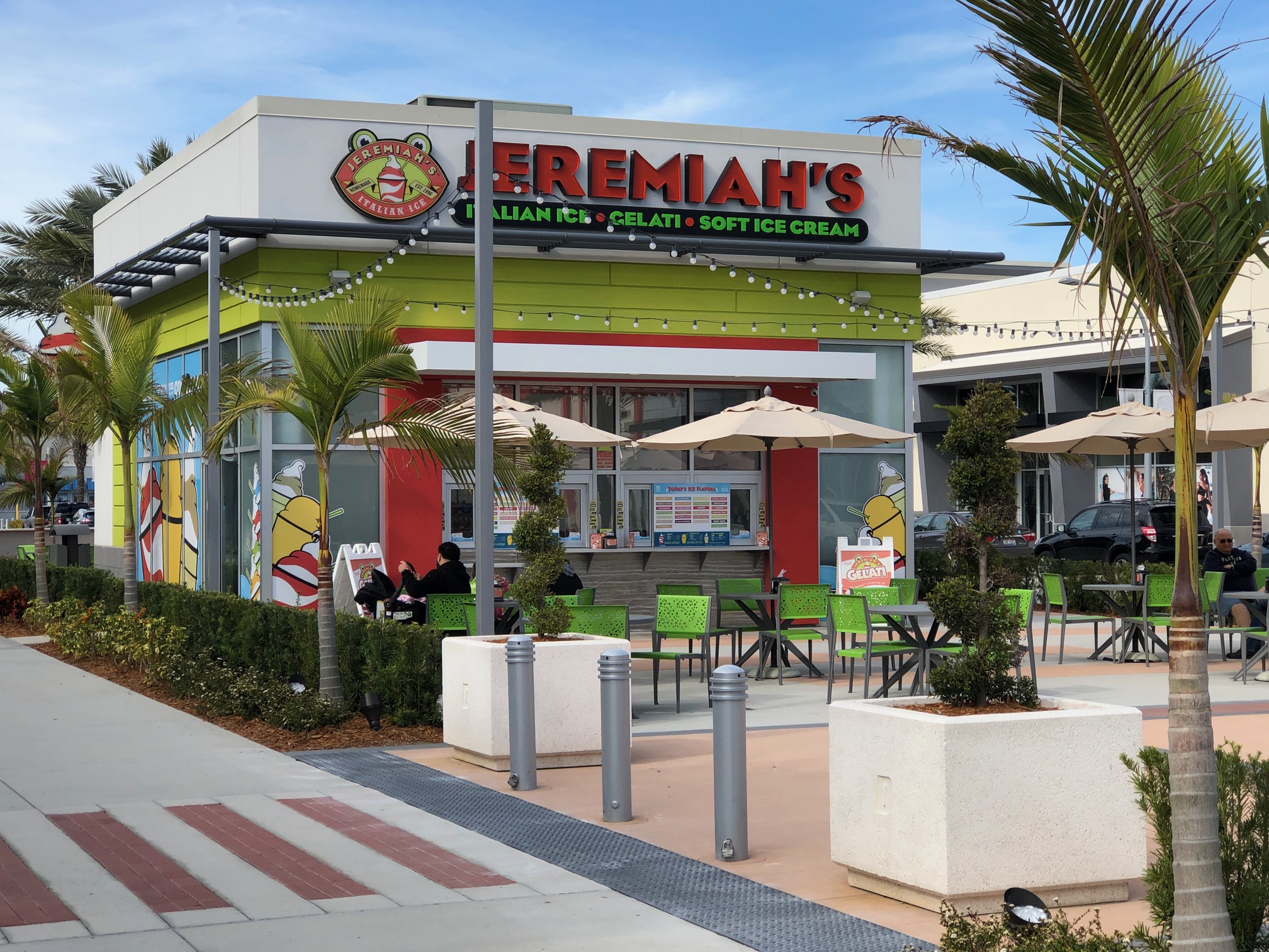 Exterior of Jeremiah’s Italian Ice business in Florida with palm trees and string lights.