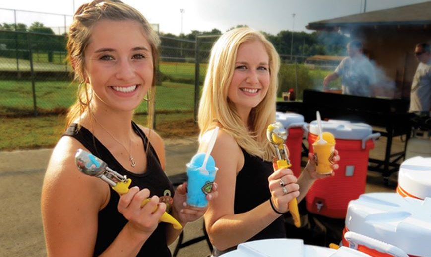 Photo of two female Jeremiah’s Italian Ice employees smiling and using ice cream scoops outside