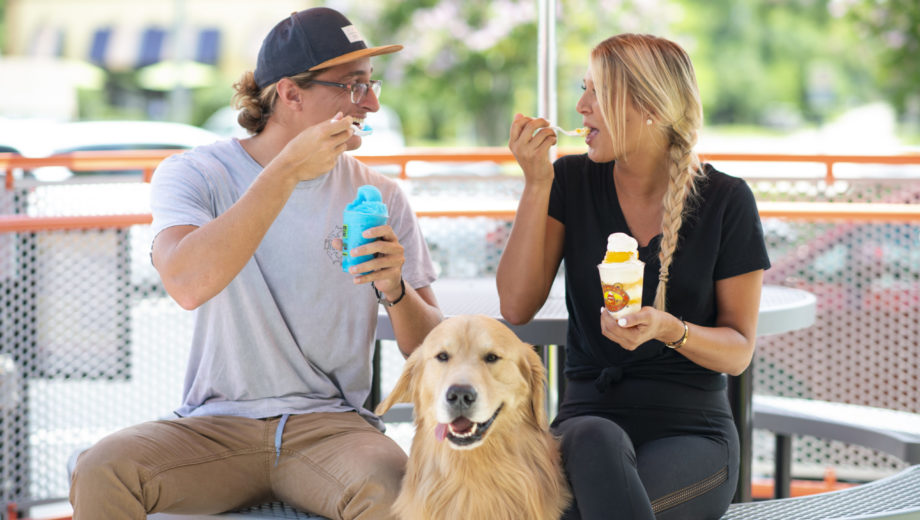 Image of two people eating frozen desserts with dog